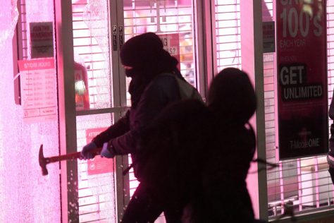 Rioters smash windows at a T-Mobile store during a protest against campus speaker